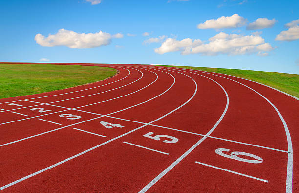 istock Running track and green grass with blue sky background. 541866520