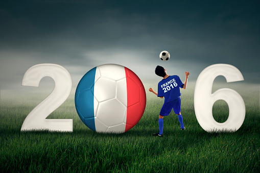 Concept of Euro 2016 France. A soccer player heading a ball with numbers 2016 and flag of France at the field