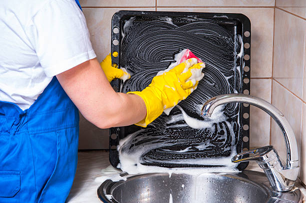 istock Female janitor with sponge cleaning dirty pan 541868990