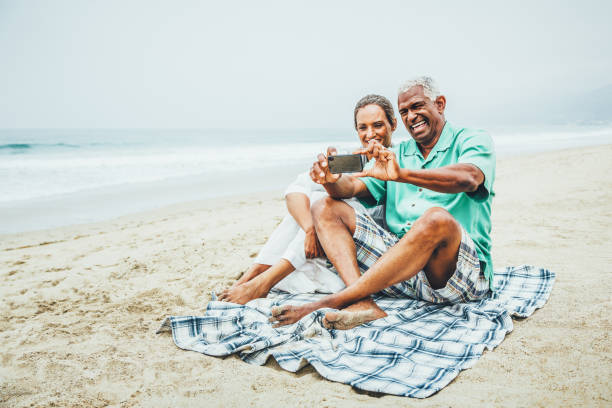 istock Senior couple having fun with smart phone on beach 541869964