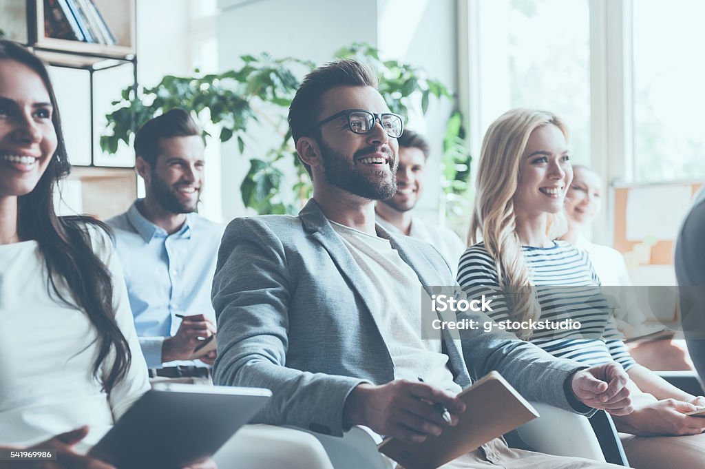 Really good seminar. Group of young people sitting on conference together and smiling Business Conference Stock Photo