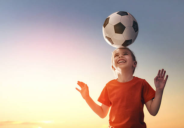 la niña juega al fútbol. - ball horizontal outdoors childhood fotografías e imágenes de stock