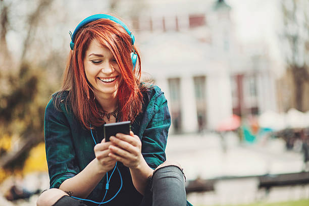 adolescente menina ouvindo música com um telefone inteligente - cabelo pintado de vermelho - fotografias e filmes do acervo