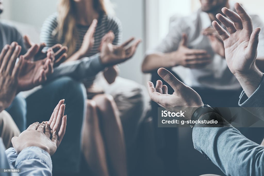 Applauding their success. Close-up of people applauding while sitting in circle together Congratulating Stock Photo