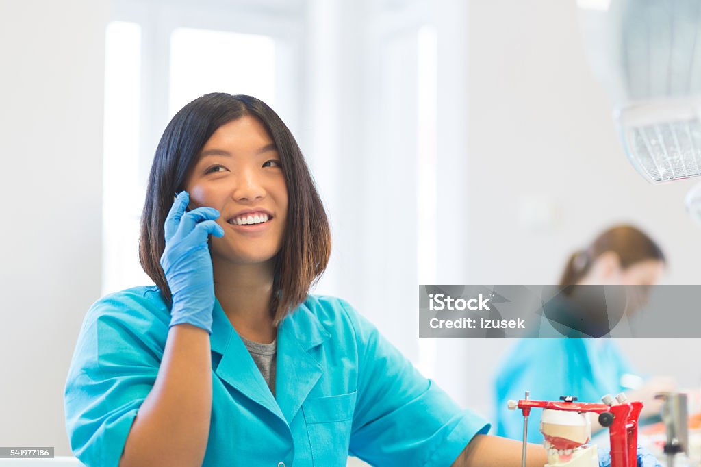 Happy asian prosthetic dentistry student talking on phone Happy asian student learning prosthetic dentistry, talking on mobile phone. Using Phone Stock Photo