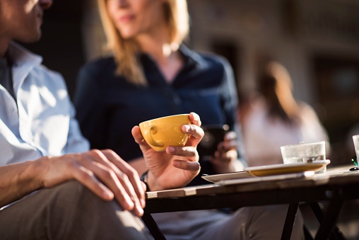 Close up of coffee cup, and young couple in background.