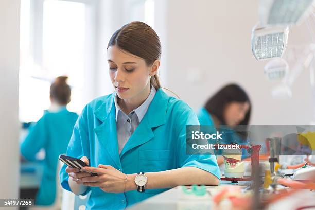 Prosthetic Dentistry Female Student Texting On Smart Phone Stock Photo - Download Image Now