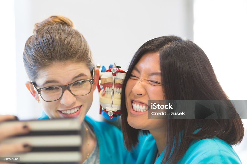 Playful prosthetic dentistry students taking selfie Happy students learning prosthetic dentistry taking selfie using smart phone. Close up of human faces and teeth. Dental Equipment Stock Photo