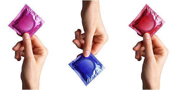 set of colored condom in female hand set of colored condom in female hand isolated on a white background condom photos stock pictures, royalty-free photos & images
