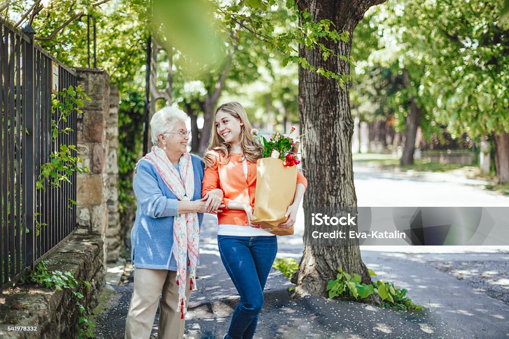 Together is easier Smiling granddaughter is helping her grandmother to carry home the packages after shopping Senior Adult Stock Photo