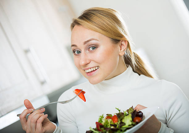 istock Happy girl with vegetable salad in kitchen 541978340