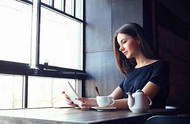 istock Young girl working on tablet computer in coffee shop 541979496