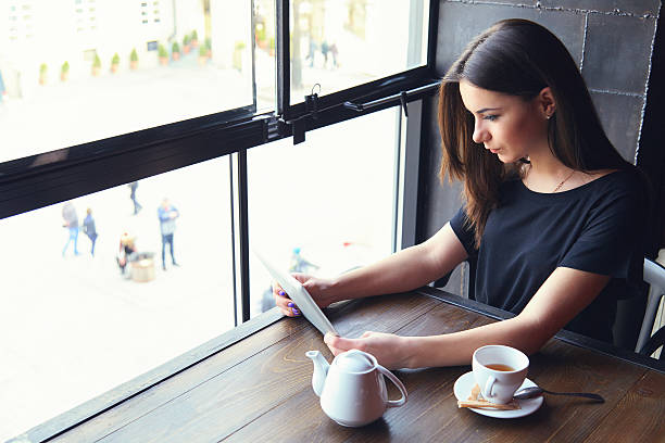 istock Young girl working on tablet computer in coffee shop 541979884