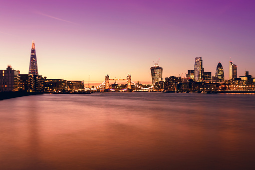London's skyline with buildings including The Shard, Tower Bridge, St Paul's Cathedral and the corporate landmarks of City of London in a pink twilight.
