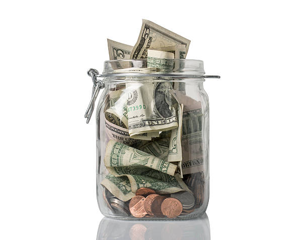 Tip Jar Overflowing A tip jar or jar for savings filled over the top with American coins and bills. bringing home the bacon stock pictures, royalty-free photos & images