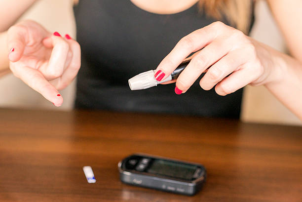 istock Closeup of young woman using lancelet on finger 541985466