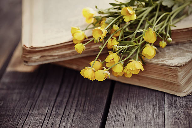 istock Old open books and buttercups on a wooden table. 541986290