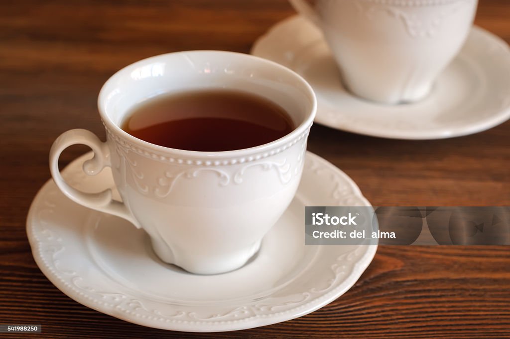 Tea in elegant teacup Black tea in an elegant teacup on a wooden table Antique Stock Photo