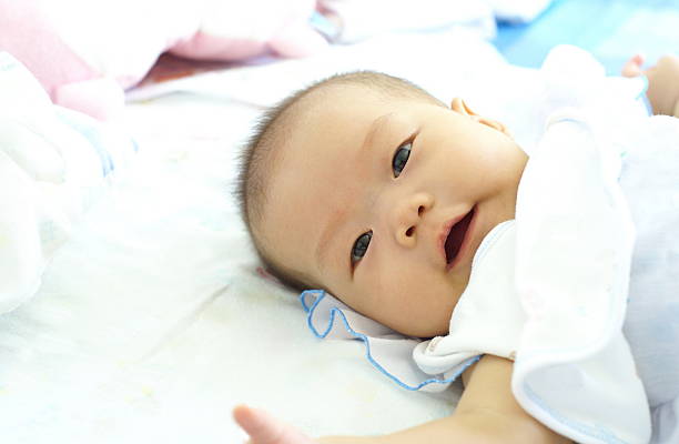 istock Cute infant lying and smiling on white bed. 541989834