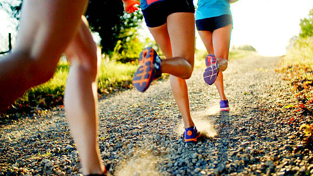 Friends Running Group of women running down gravel road. off track running stock pictures, royalty-free photos & images