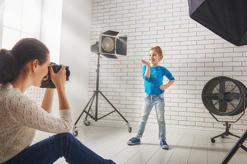 Photographer in motion. Young woman photographs of the child.