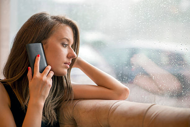 istock Pensive women using smartphone and  sitting near window 541992666