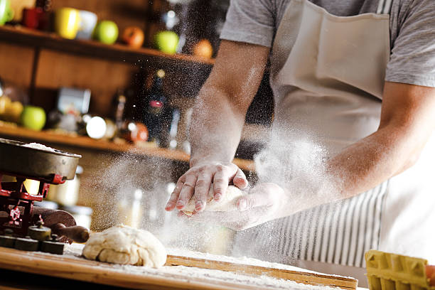 Male baker prepares bread. Male baker slaps on dough. Making bread.