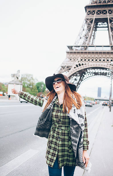 istock Laughing woman with thumb up for hitch-hiking at Eiffel tower 541995224