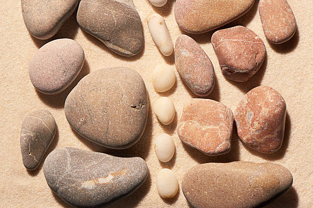istock Pink and grey sea stones separated by white on sand 541996990