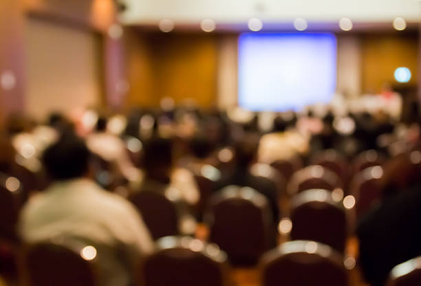 istock Blur  row  of  audience  sitting   in  auditorium with screen 541998380