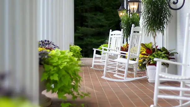 Rocking chairs sitting outside on the front porch of a home with white columns.
