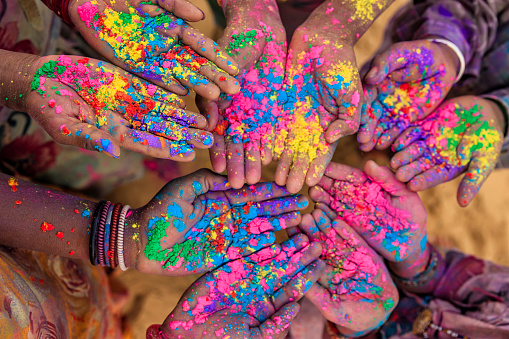 Group of Indian children playing happy holi in Rajasthan, India. Indian children keeping their hands up and showing colorful powders. Holi, the festival of colors, is a religious festival in India, celebrated, with the color powders, during the spring.