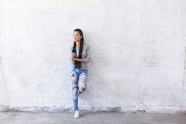 istock Young asian woman leaning on blank wall 542006052