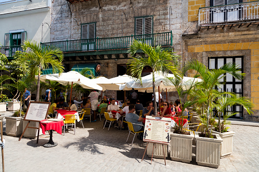 Havana, Сuba - April 20, 2016: People enjoying lunch break at street restaurant, Old Town, Havana, Cuba. Buildings in traditional colonial style are visible in the background, 50 megapixel image.