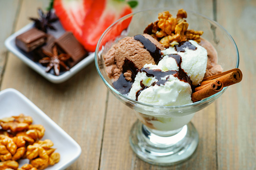 Ice cream sundae, chocolate, walnuts and sliced strawberry on a table