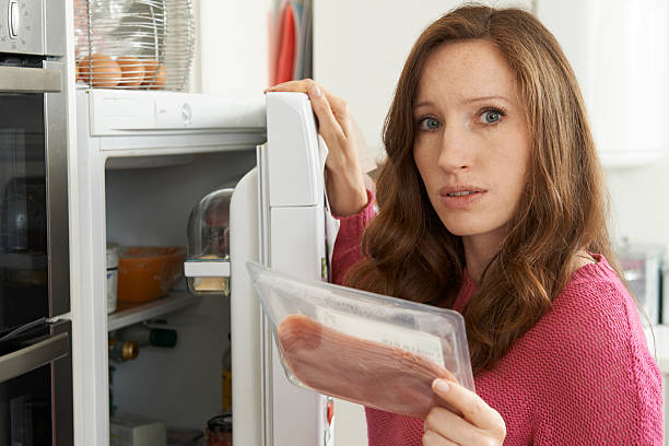 besorgt frau schaut an fleisch vor package - packaged food stock-fotos und bilder