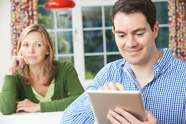 istock Unhappy Woman Sitting At Table As Partner Uses Digital Tablet 542012312