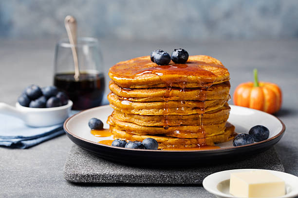 frittelle di zucca con sciroppo d'acero e mirtilli su un piatto. - honey caramel syrup fruit foto e immagini stock