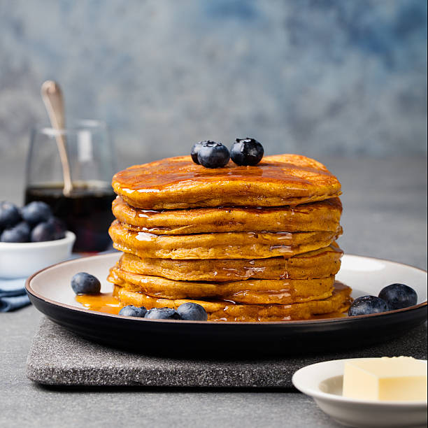istock Pumpkin pancakes with maple syrup and blueberries on a plate. 542012674