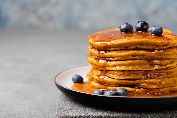 istock Pumpkin pancakes with maple syrup and blueberries on a plate. 542012798
