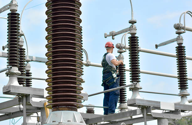 Electrician Working in Power Substation Construction worker with hadhat, protective workwear and safety belt working in power plant. safety first at work stock pictures, royalty-free photos & images