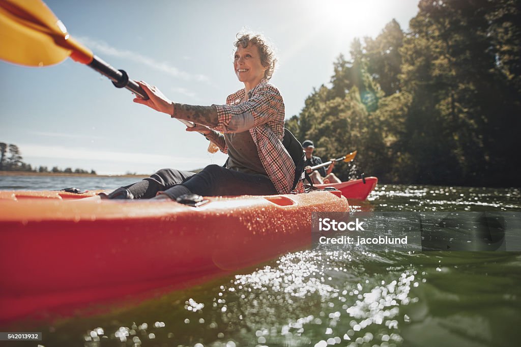 Senior woman canoeing in lake on a summer day Shot of senior woman canoeing in lake on a summer day. Mature woman paddling a kayak in lake. Mature Women Stock Photo