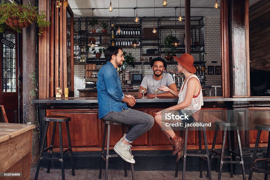 Young people sitting in a cafe and talking Group of young people sitting in a cafe and talking. Young men and women meeting at cafe table. Bar Counter Stock Photo