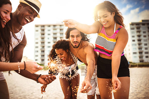 istock friends using a sparkler togetherness on the beach 542065084