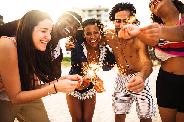 istock friends using a sparkler togetherness on the beach 542065200