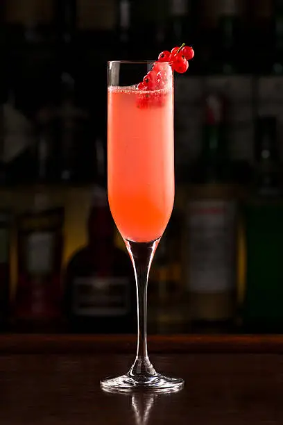 Elegant redcurrant champagne cocktail on wooden bar