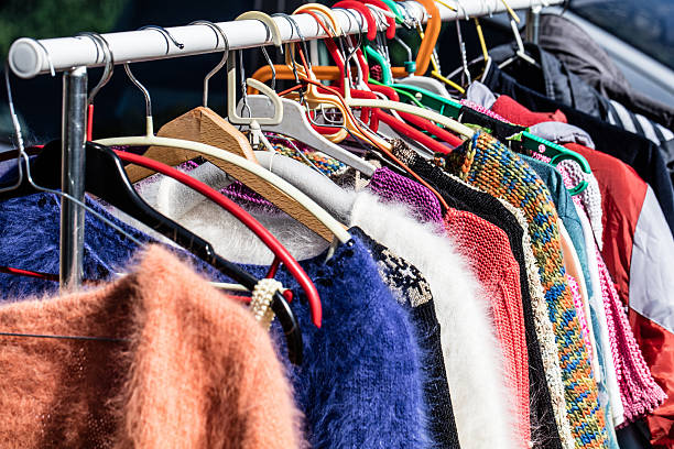 colored second hand women's sweaters at flea market colored second hand women's sweaters on display for reselling,recycling,donation,reusing or welfare for second life sold at flea market, outdoors clothing swap photos stock pictures, royalty-free photos & images