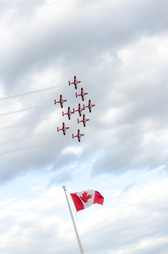 Quebec, Canada - June 15, 2016: Nine Canadian Snowbirds aircraft flying overTerrace Dufferin with a Canadian Flag floating at bottom during day of summer