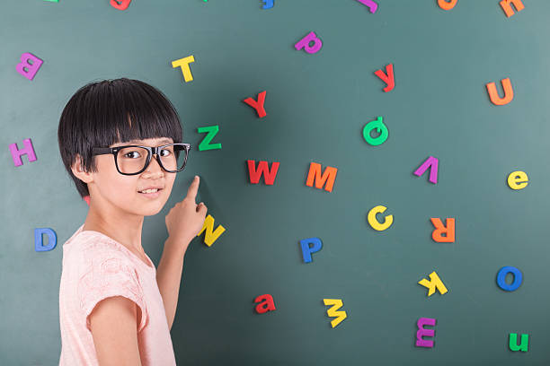 istock girl poiting to blackboard with letters 542076388