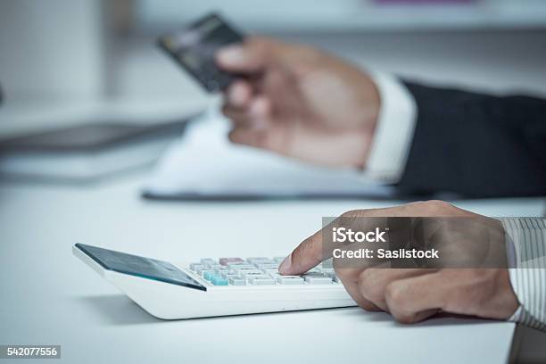 Businessman Using A Calculator To Calculate His Payment On Credi Stock Photo - Download Image Now